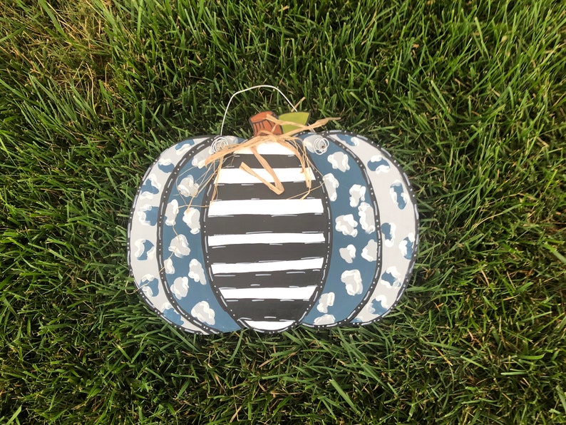 Puede incluir: Un colgador de puerta de calabaza azul y blanco con un patr&oacute;n de rayas blancas y negras y un dise&ntilde;o de estampado de leopardo.