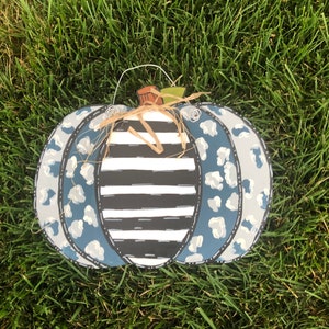 Puede incluir: Un colgador de puerta de calabaza azul y blanco con un centro a rayas blanco y negro. La calabaza est&aacute; decorada con un estampado de leopardo.