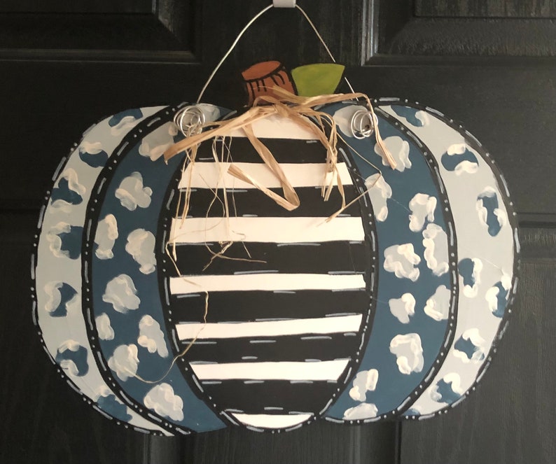 Puede incluir: Una calabaza a rayas azul y blanca con un dise&ntilde;o de estampado de leopardo azul y blanco. La calabaza est&aacute; decorada con un tallo marr&oacute;n y un lazo de paja.