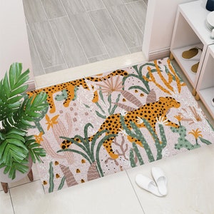 May include: A pink and white rug with a jungle theme. The rug features a repeating pattern of green plants, cacti, and orange and brown leopards.