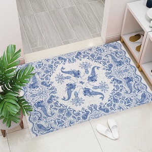 Puede incluir: Una alfombra de patrón blanco y azul con un diseño central de sirenas y un pulpo. La alfombra tiene un borde de estilo paisley.