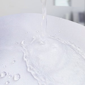 K&ouml;nnte beinhalten: Nahaufnahme eines wei&szlig;en Stoffes mit Wassertropfen und einem Wasserstrahl, der herunterflie&szlig;t. Der Stoff hat eine strukturierte Oberfl&auml;che, und das Wasser erzeugt einen dynamischen visuellen Effekt. Das Bild hebt die F&auml;higkeit des Stoffes hervor, Wasser abzuweisen.