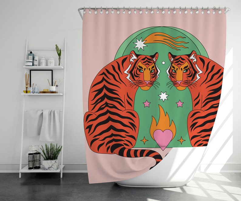 K&ouml;nnte beinhalten: Duschvorhang mit Retro-Design. Er zeigt zwei orangefarbene Tiger, die sich vor einem gr&uuml;nen Hintergrund mit Sternen, einem Sternschnuppen und einem rosa Herzen mit Flammen gegen&uuml;berstehen. Der Hintergrund ist hellrosa.