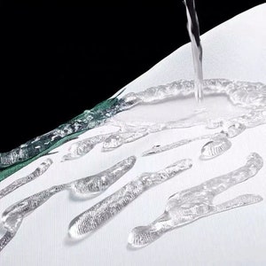K&ouml;nnte beinhalten: Nahaufnahme von Wassertropfen auf einem wei&szlig;en Stoff. Wasser wird auf den Stoff gegossen, was die Wasserbest&auml;ndigkeit demonstriert. Der Stoff hat ein gr&uuml;n-wei&szlig;es Muster am Rand.