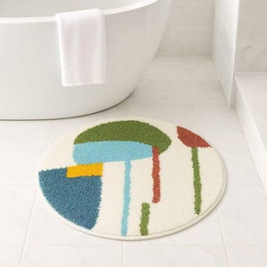 May include: A round, white bath mat with a colorful abstract design. The design features geometric shapes in shades of green, blue, yellow, and red.