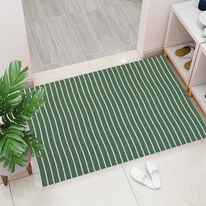 May include: A green and white striped doormat with a wavy pattern. The doormat is made of a soft, durable material and is perfect for adding a touch of style to any entryway.