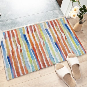 May include: A colorful doormat with a watercolor stripe design in shades of blue, orange, yellow, and red. The doormat is made of a durable material and is perfect for adding a touch of color to any entryway.