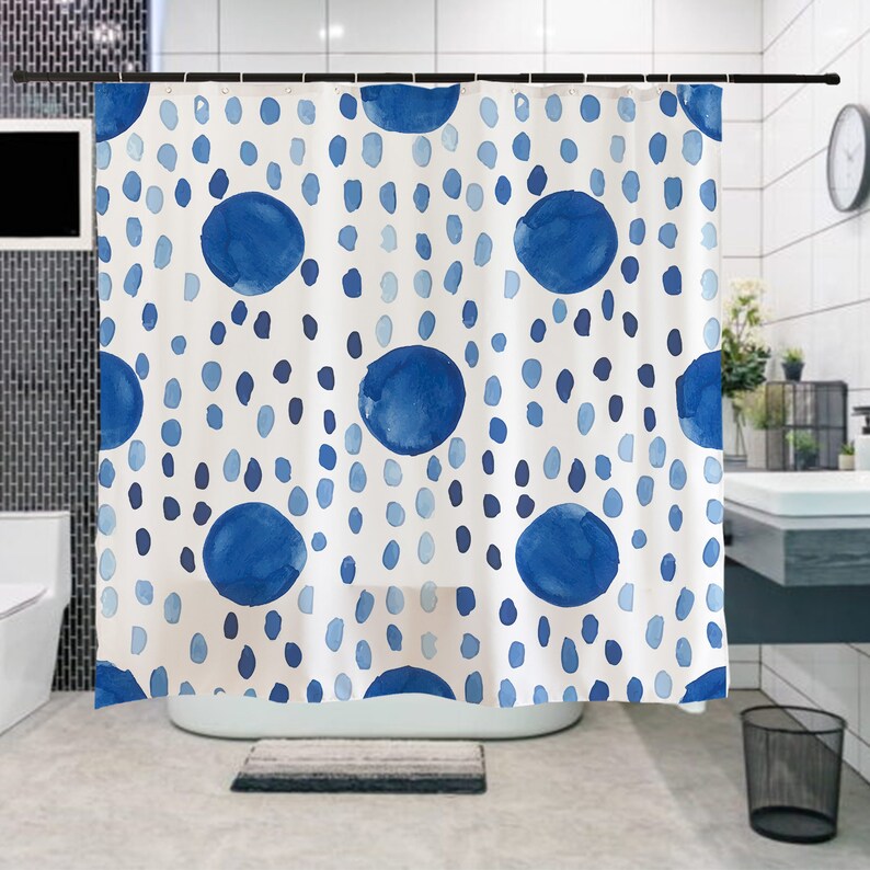 May include: A white shower curtain with a blue watercolor polka dot pattern. The dots are of varying sizes and are arranged in a random pattern.