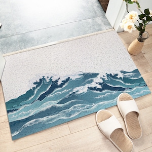 May include: A white doormat with a blue and white wave design. The doormat is made of a textured material and has a subtle sparkle.