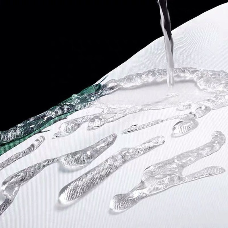 May include: Water droplets beading on a white fabric surface, demonstrating its water-resistant properties.