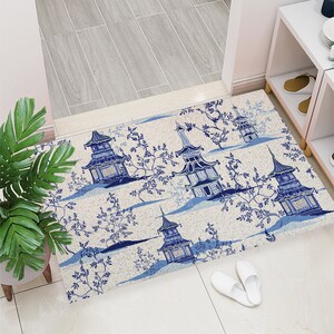 May include: A white and blue doormat with a repeating pattern of blue pagodas and stylized floral branches. The doormat has a textured surface.