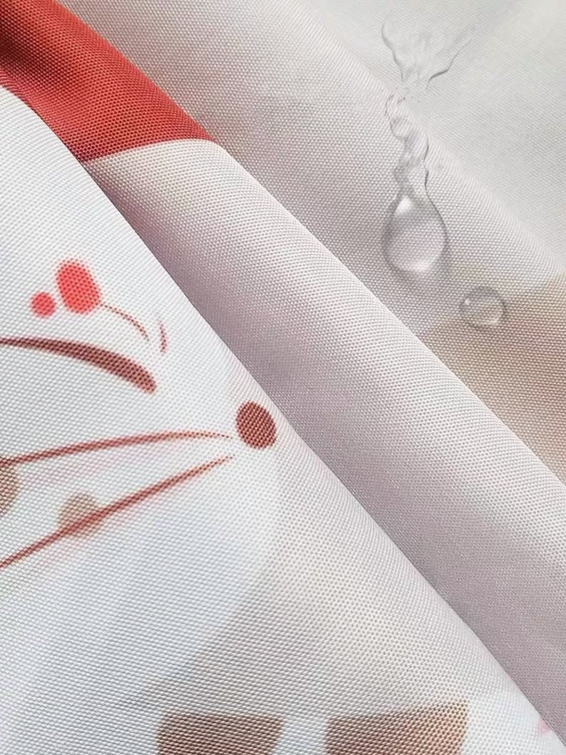 K&ouml;nnte beinhalten: Nahaufnahme eines wei&szlig;en Stoffes mit rotem Streifen und floralem Design. Der Stoff hat eine subtile Textur und ist leicht gefaltet, mit Wassertropfen auf der Oberfl&auml;che. Das Design umfasst braune und rote florale Elemente.