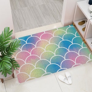 Puede incluir: Una alfombra de entrada colorida con un patrón de escamas de sirena en tonos de rosa, azul, verde y amarillo. Las escamas están delineadas en blanco.