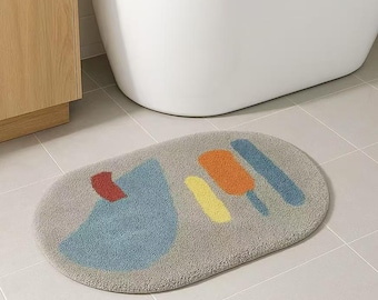 May include: A gray oval bath mat with a blue, yellow, orange, and red abstract design.