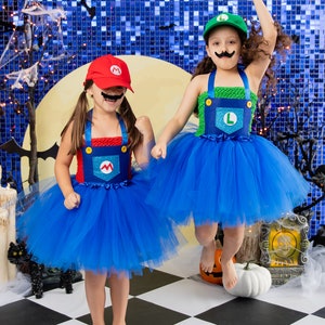 Puede incluir: Dos ni&ntilde;os disfrazados de Mario y Luigi para Halloween. Llevan tut&uacute;s de tul azul con monos rojos y verdes. La ni&ntilde;a disfrazada de Mario lleva un sombrero rojo con una 'M' y un bigote negro. La ni&ntilde;a disfrazada de Luigi lleva un sombrero verde con una 'L'. Est&aacute;n de pie sobre un suelo de ajedrez negro y blanco.