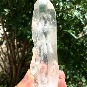 Peut inclure: Une pointe de cristal de quartz clair avec une double terminaison. Le cristal mesure environ 15 cm de long et a une apparence naturelle et brute.