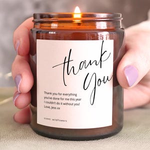 Personalised thank you candle in amber glass jar with custom message label, lit and held in hands, gratitude gift idea