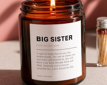 May include: A burning amber glass candle with a "BIG SISTER" label, and a small glass vial of matches. The candle's scent is "fresh linen." The candle is a decorative item.