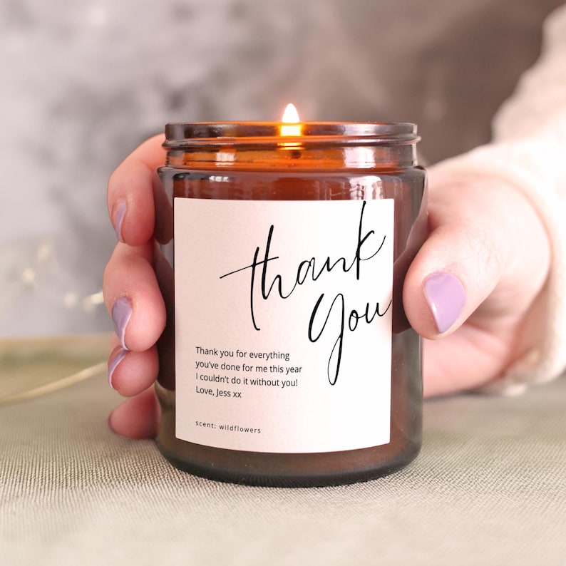 Personalised thank you candle in amber glass jar with custom message label, lit and held in hands, gratitude gift idea