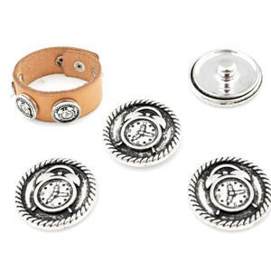 Könnte beinhalten: Vier silberfarbene Metall-Druckknöpfe mit einem Zifferblattmuster. Die Knöpfe sind von einem seilartigen Rand umgeben. Die Knöpfe sind auf einem braunen Lederarmband abgebildet.
