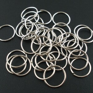 May include: A pile of silver jump rings, a type of metal ring used in jewellery making.