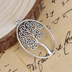 Puede incluir: Encanto de metal plateado en forma de árbol de la vida. El árbol tiene un diseño detallado con ramas y hojas en espiral. El encanto es de forma ovalada y tiene un bucle en la parte superior para sujetarlo a un collar o pulsera.