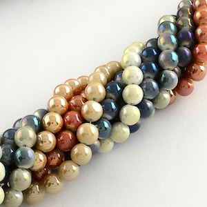 Può includere: Un filo di perline di vetro iridescenti in tonalità beige, marrone, blu e verde. Le perline sono disposte a spirale.
