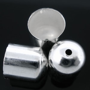 May include: Three silver metal end caps for jewellery making. The end caps are round and have a smooth, shiny finish.