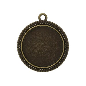 May include: A round, antique gold-toned metal pendant with a smooth, circular surface and a beaded edge. The pendant has a loop at the top for attaching a chain or cord.