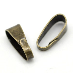 May include: Two antique bronze-colored pendant bails on a white background. The bails are oval-shaped with a loop at the top and a flat base. They are made of metal and have a vintage finish, perfect for jewelry making.