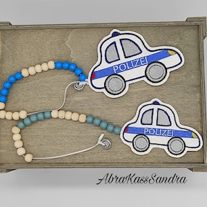 Könnte beinhalten: Eine Holzperlenkette mit blauen und hellblauen Perlen. Zwei weiße und blaue gestickte Polizeiauto-Aufnäher mit dem Wort "Polizei" sind an der Kette befestigt.