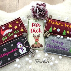 Peut inclure: Cinq porte-cartes cadeaux de Noël en feutre. Les porte-cartes sont décorés de différents thèmes de Noël, notamment un bonhomme de neige, un renne, un sapin de Noël et un chapeau de Père Noël. Les porte-cartes sont tous rectangulaires et ont une fente au milieu pour insérer une carte cadeau.