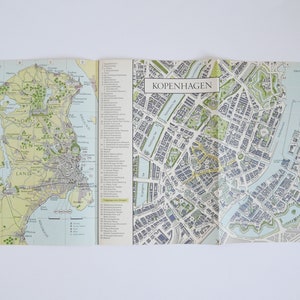 Könnte beinhalten: Eine gefaltete Vintage-Karte von Kopenhagen, Dänemark. Die Karte zeigt den Grundriss der Stadt mit Straßen, Wasserwegen und Sehenswürdigkeiten. Die Karte ist in der oberen rechten Ecke mit "København" betitelt.