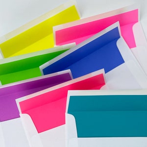 7 white envelopes with various neon envelope liners