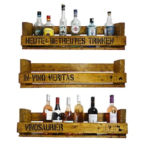May include: Three wooden shelves with a rustic finish, each with a different saying. The top shelf says "Heute: Betreutes Trinken", the middle shelf says "In Vino Veritas", and the bottom shelf says "Vinosaurier". The shelves are filled with various bottles of wine and liquor.