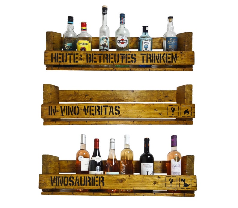 May include: Three wooden shelves with a rustic finish, each with a different saying. The top shelf says "Heute: Betreutes Trinken", the middle shelf says "In Vino Veritas", and the bottom shelf says "Vinosaurier". The shelves are filled with various bottles of wine and liquor.