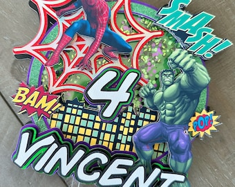 May include: A multi-layered cake topper featuring Spider-Man and the Hulk. The design includes the number "4", the name "Vincent", and comic book style exclamations like "BAM!" and "SMASH!". The color scheme includes red, blue, green, and purple.