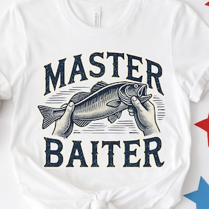 Könnte beinhalten: Weißes T-Shirt mit dem Schriftzug "MASTER BAITER" in Dunkelblau und einer Grafik eines Fisches, der von Händen gehalten wird. Das T-Shirt ist an der Taille geknotet. Rote, weiße und blaue Sterne sind verstreut.
