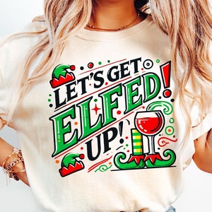 May include: A cream colored t-shirt with a green and red graphic that says "Let's Get Elfed Up!" with a glass of wine and elf shoes.
