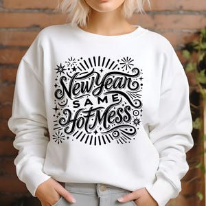 May include: White sweatshirt with black text that reads "New Year Same Hot Mess" with a decorative design of stars and fireworks.