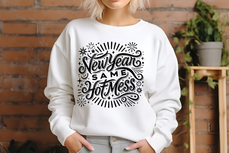 May include: White sweatshirt with black text that reads "New Year Same Hot Mess" with a decorative design of stars and fireworks.