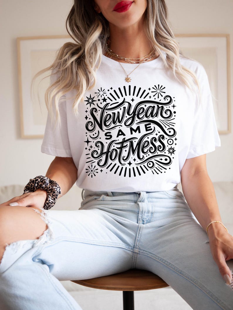 May include: White t-shirt with black text that reads "New Year Same Hot Mess" surrounded by stars and fireworks.