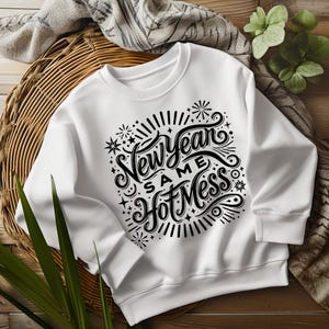 May include: White sweatshirt with a black graphic print that says "New Year Same Hot Mess" with stars and fireworks around the text.