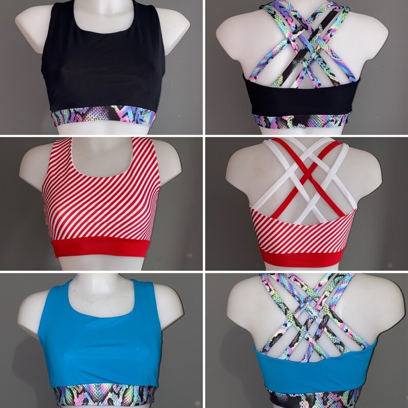 Op de afbeelding: Drie verschillende sportbeha's met verschillende patronen en kleuren. De eerste beha is zwart met een kleurrijk slanghuidpatroon, de tweede is rood-wit gestreept met een witte kruisband en de derde is blauw met een kleurrijk slanghuidpatroon.
