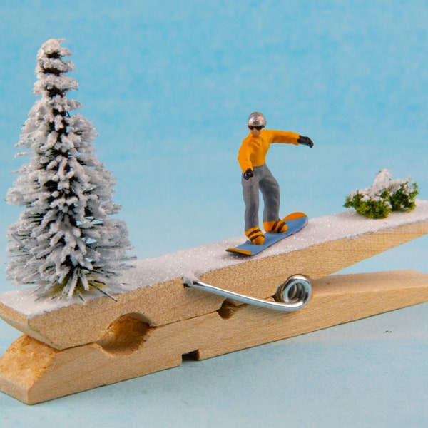 Miniature, clothespin snowboard on the slopes