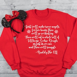 May include: A bright red long-sleeve crewneck sweatshirt featuring white cursive text that reads: First we'll make snow angels for two hours, then we'll go ice skating then we'll eat a whole roll of tollhouse Cookie Dough as fast as we can, and then we'll snuggle -Buddy The Elf. A black sequined headband with a red sequined bow is placed on the left shoulder.