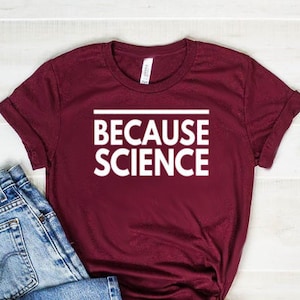 May include: A maroon t-shirt with the text "Because Science" in white letters.