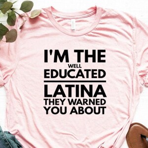 May include: Pink t-shirt with the text "I'm the well educated Latina they warned you about" printed in black.