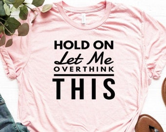 May include: Pink t-shirt with black text that reads "Hold On Let Me Overthink This".