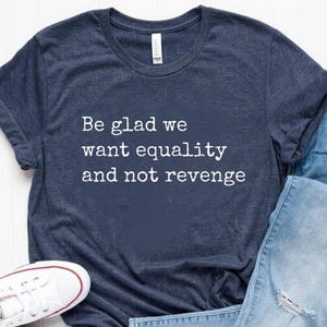 May include: A navy blue t-shirt with the text "Be glad we want equality and not revenge" printed in white.